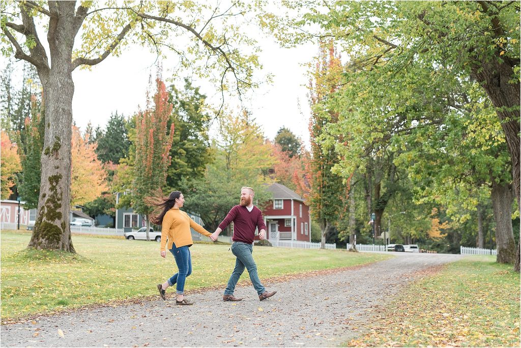 Couple takes a walk in fall leaves in Port Gamble, Washington